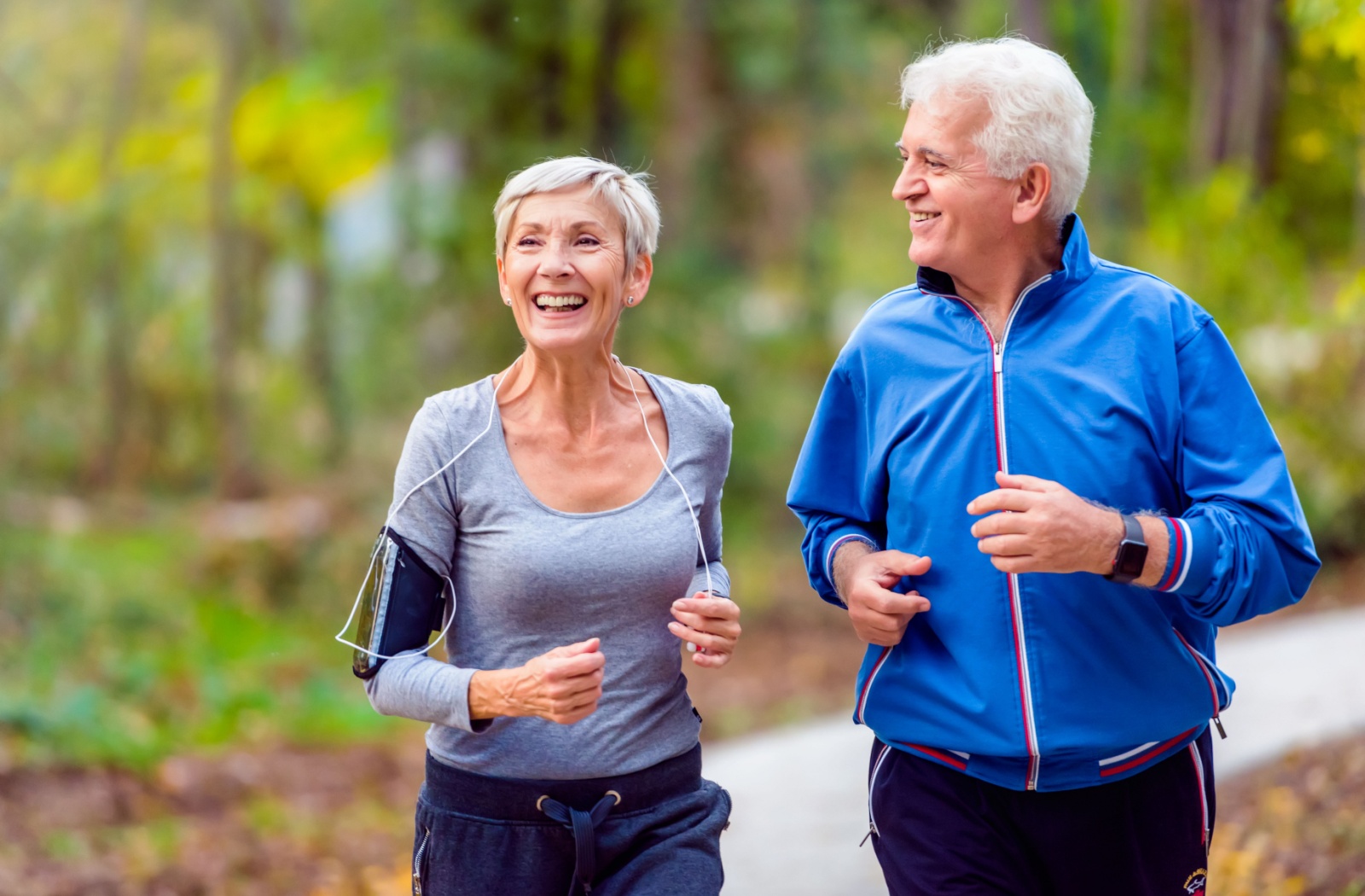 A senior couple jogging on a woodland trail
