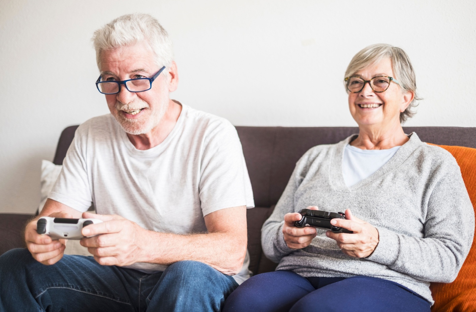 Senior couple playing video games together on the couch.
