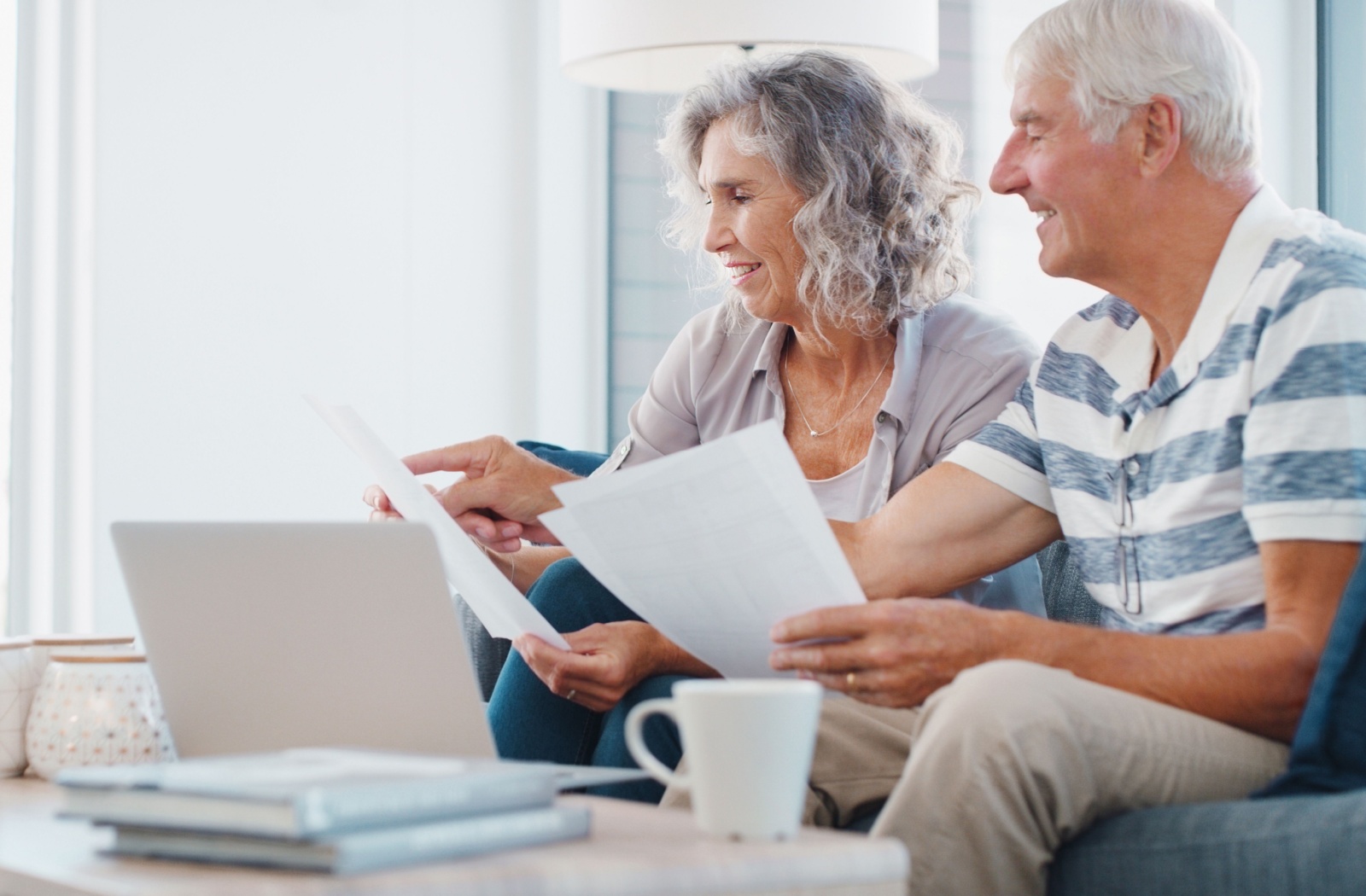 A senior couple doing paperwork and pointing at a computer screen, trying to make a financial plan for their move to senior living.
