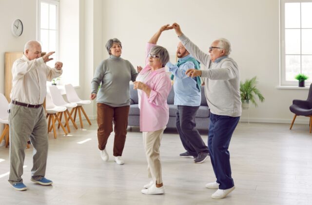 Residents of a life plan community dancing and staying active together in a bright indoor space