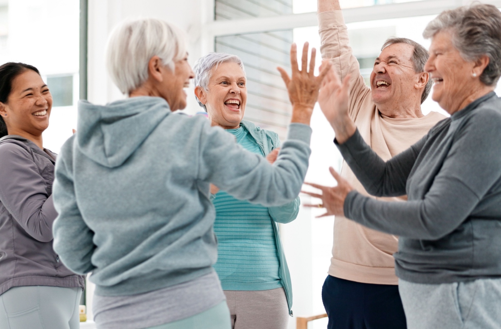 Seniors enjoying an active social life in a life plan community, laughing and participating in a fun group exercise together.
