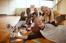 A friend group of older adults relaxes after playing basketball.